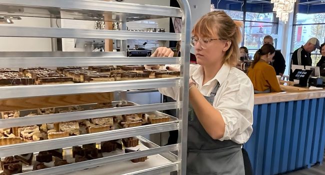 Student selecting baked goods for customers at SCCC's Bakeshop